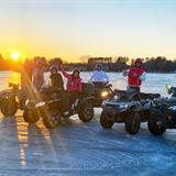 Group of people on ATVs on top of a frozen lake.