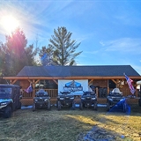 A lineup of vehicles in front of a log cabin.
