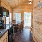 Interior with kitchen, range, kitchen table, chairs, futon, and bunk beds.