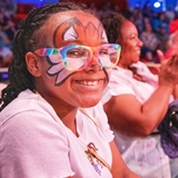 Girl with a face painting smiling at the camera.
