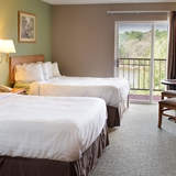 Two bed bedroom with table, chairs, television, and outdoor patio.