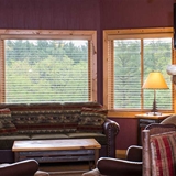 Living area with sofa, arm chairs, television, and stone fireplace.