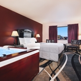 Two bed bedroom with night stand, lamps, table, chairs, and television.