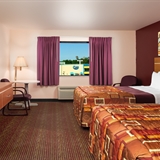 Three bed bedroom with sofa, table, chairs, television, night stands, and lamps.