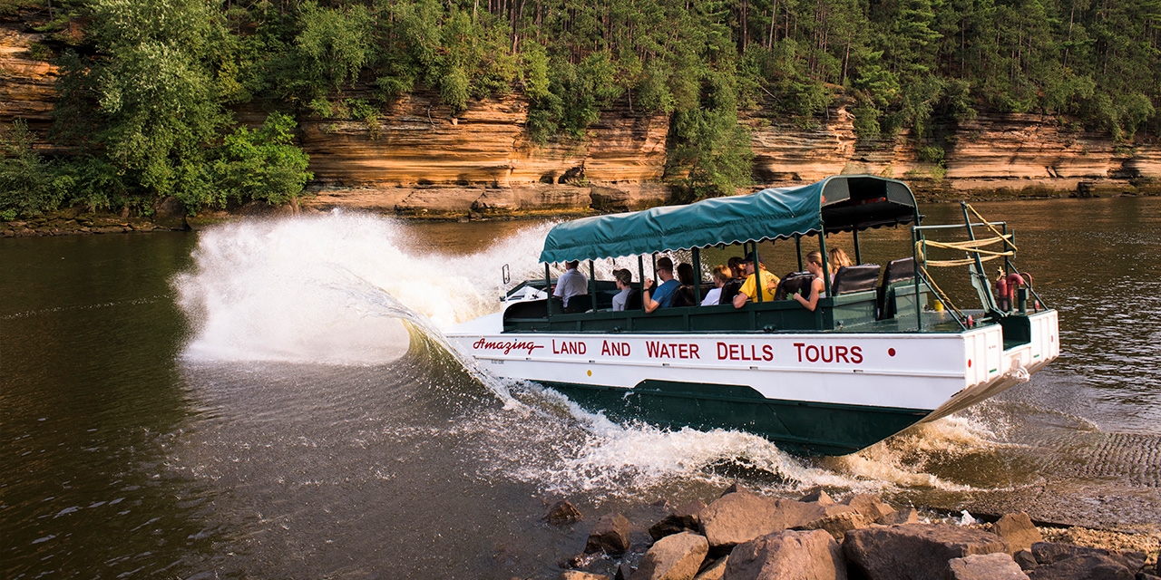 A duck boat splashes into the water.