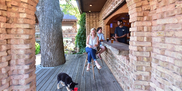Couple sitting at an outdoor bar with their dog.