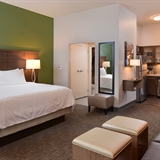 Bedroom with sofa, desk, office chair, lamp, and kitchenette.